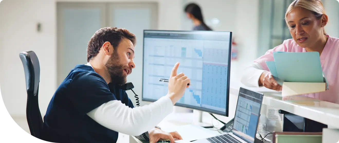 Healthcare worker and administrator reviewing data dashboards together at a hospital workstation