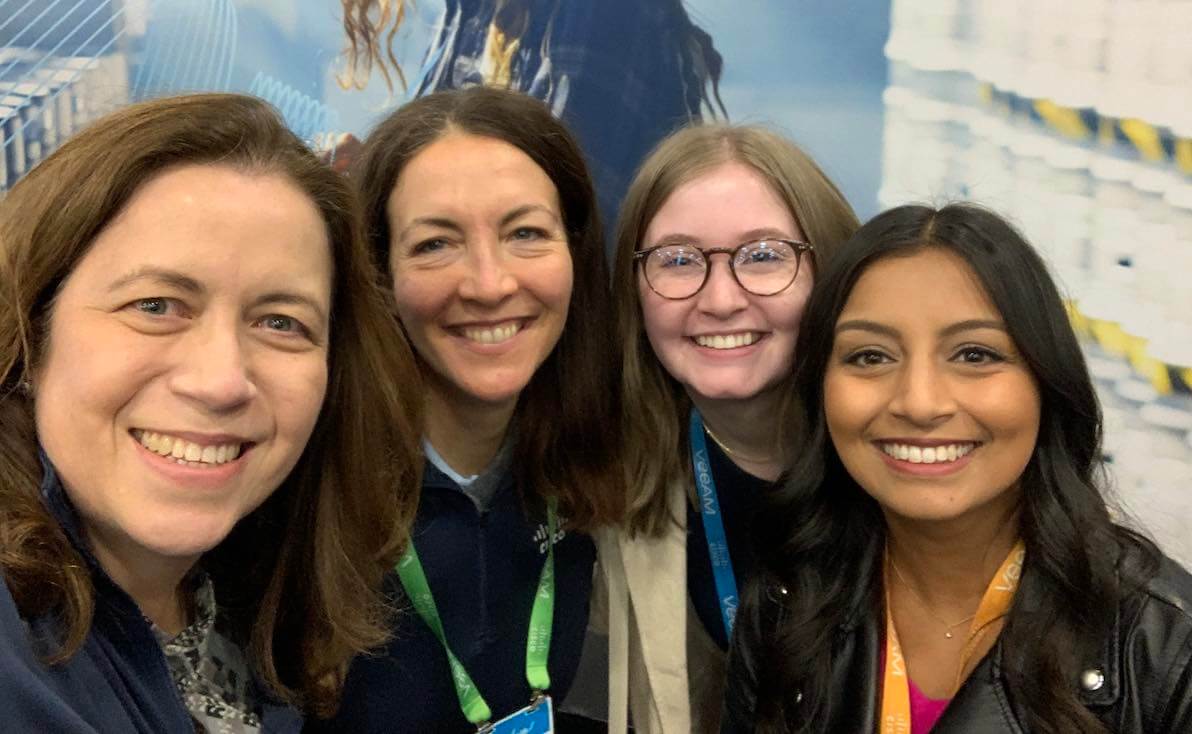 Four women pose together at a conference