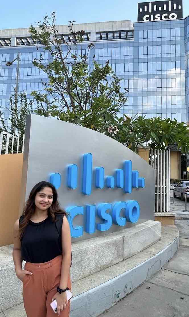 One of the Cisco Interns poses in front of the Cisco sign at the office.