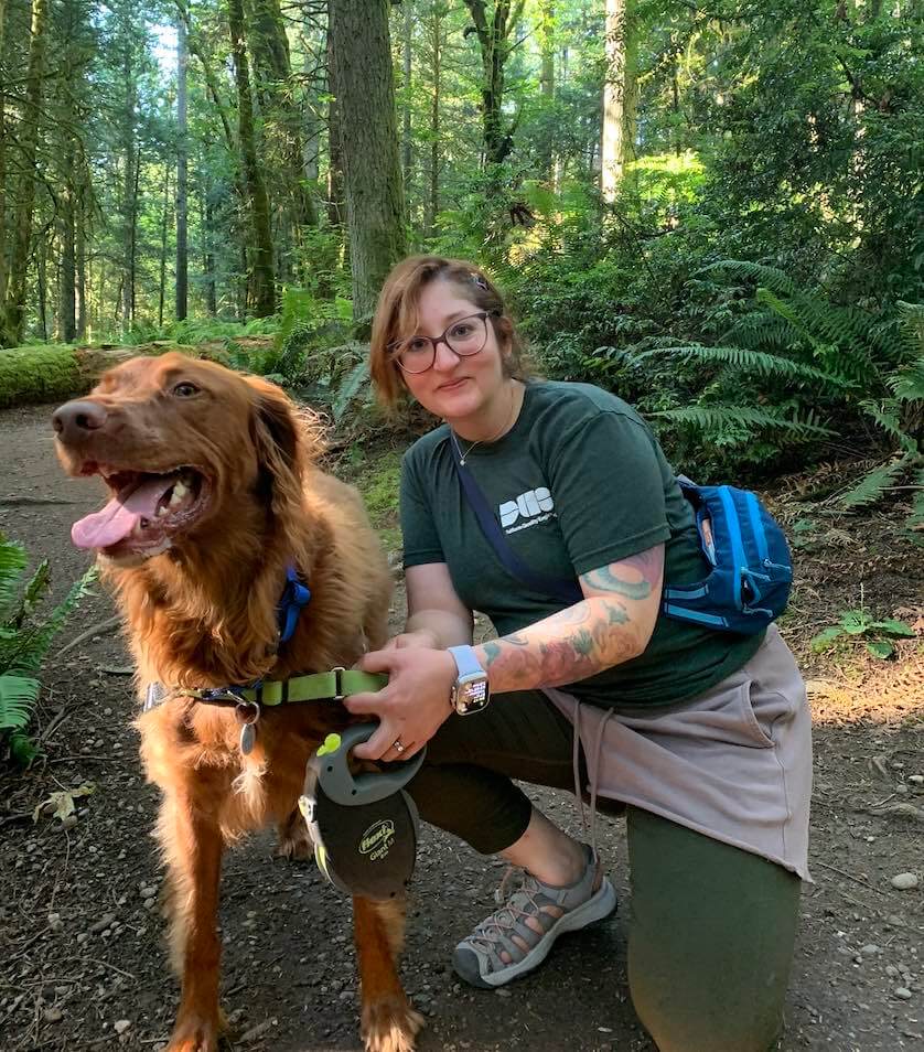 Laura Garza poses with her dog Alfie Cornelius Garza - who appears to be a golden retriever - while on a hike in the forest