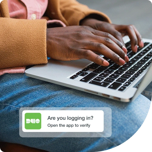 Trusted user working on a laptop using Duo multi-factor authentication with a simple prompt to gain secure access.