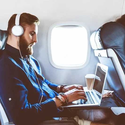 Professional using a laptop on an airplane, representing secure mobile and remote authentication for enterprise environments.