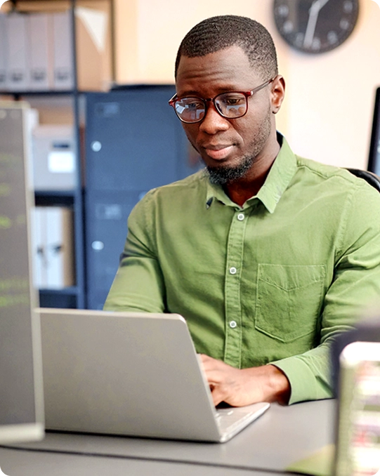 Man in glasses types on a laptop in an office