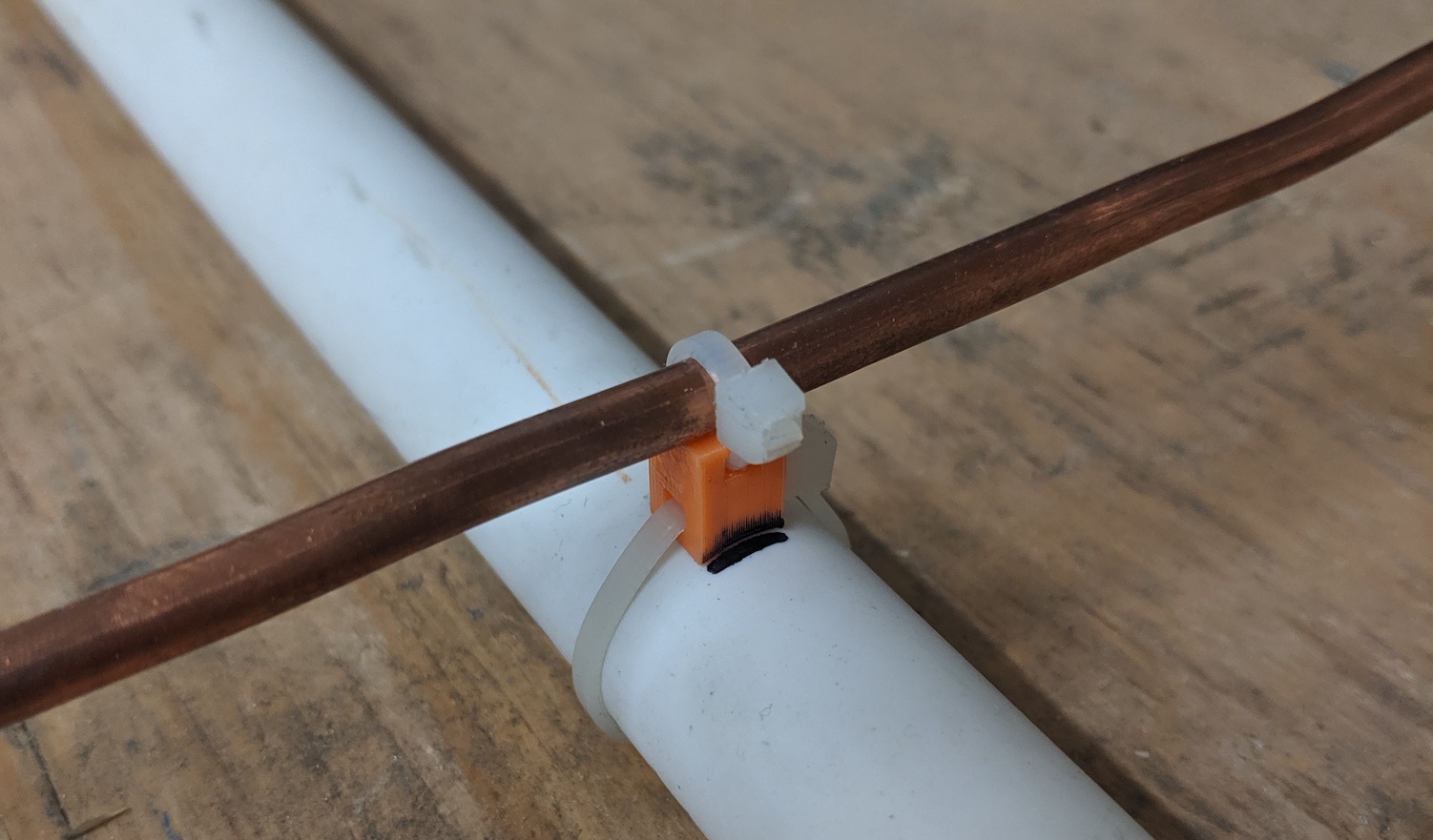 Photo of an antenna element that is zip-tied to a 3d-printed standoff that is zip-tied to a PVC pipe with a Sharpie mark on the PVC pipe