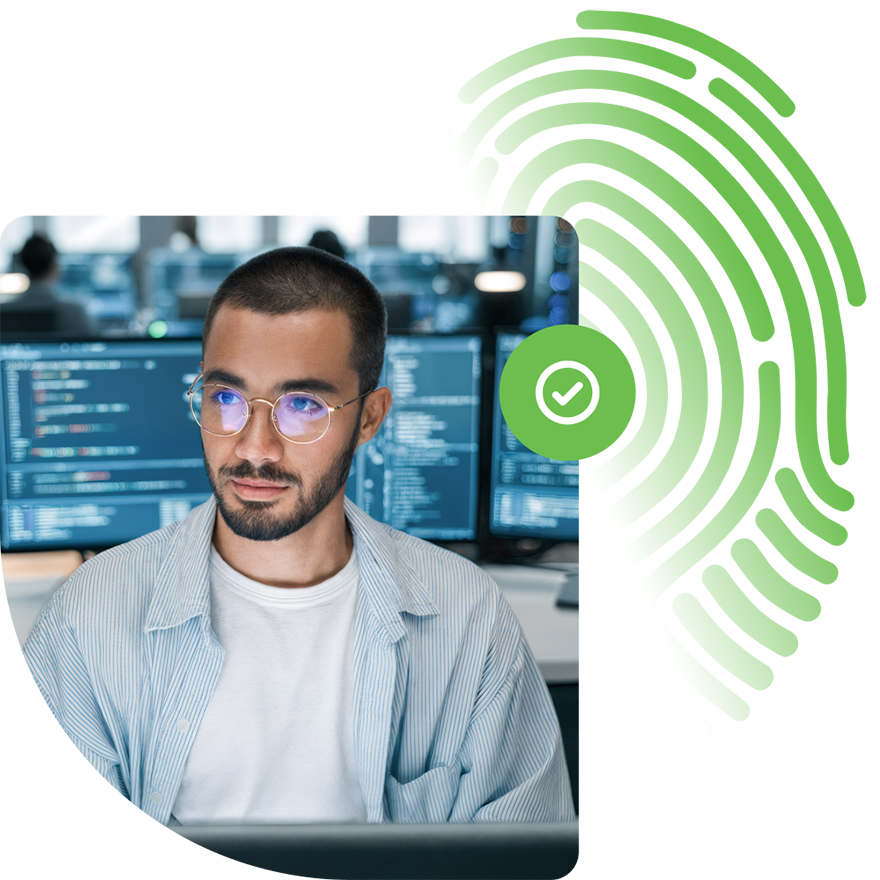 A cyber security expert working at a computer in a modern office. Behind him, multiple monitors display lines of computer code. A green fingerprint graphic with a checkmark overlays the right side of the image, suggesting data security or identity verification.