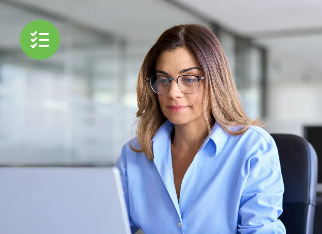 A woman securely accessing her laptop in a modern office, with a green access secured confirmation badge symbolizing verified privileged access