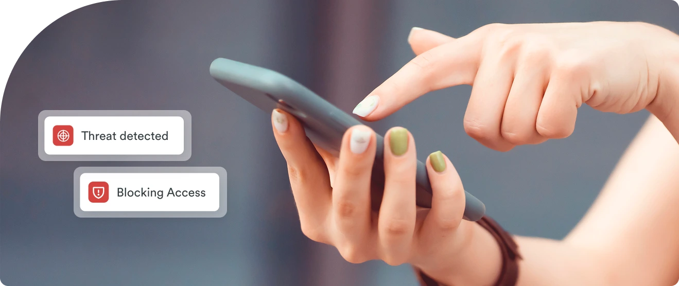 Hands holding a smartphone with Duo security alerts showing 'Threat detected' and 'Blocking Access' in response to an identity-based attack.