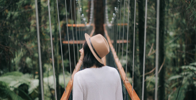 A person crosses a bridge over lush greenery, representing transitions for smart cards.