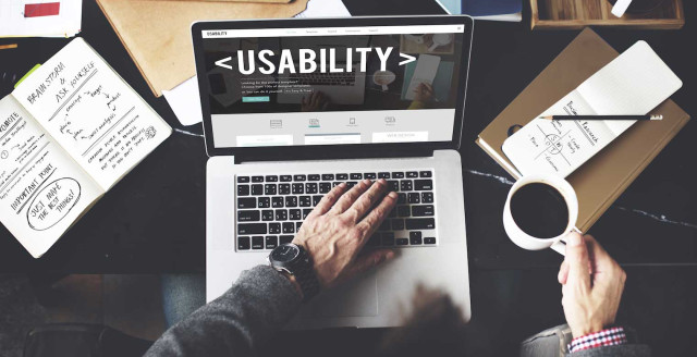 The word usability appears on a laptop screen in huge font, representing how essential accessibility is to usability and security.