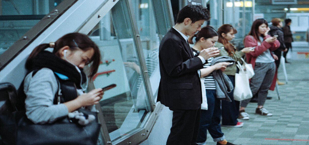 People on a platform looking at mobile devices and reading