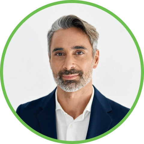 Smiling man with gray hair and beard wearing a suit jacket and white shirt.